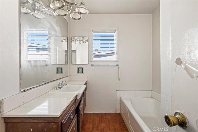 bathroom featuring a tub to relax in, plenty of natural light, wood finished floors, and vanity