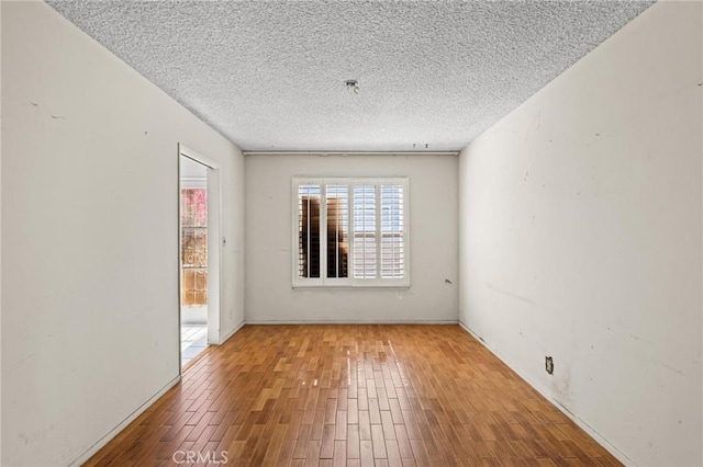 spare room with a textured ceiling and wood finished floors