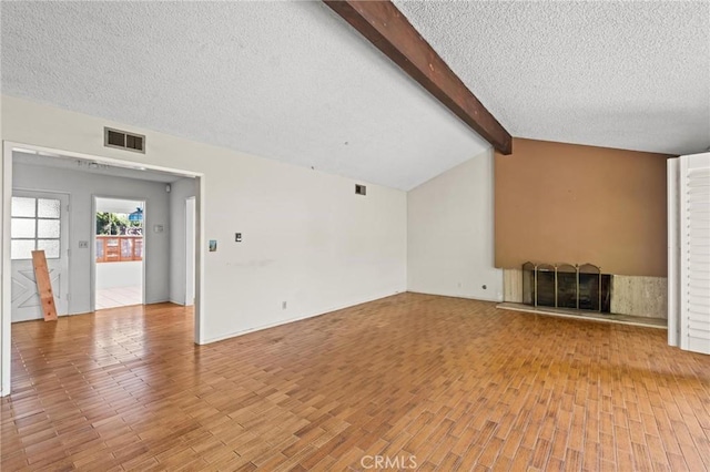 unfurnished living room featuring vaulted ceiling with beams, a fireplace with raised hearth, a textured ceiling, visible vents, and light wood finished floors