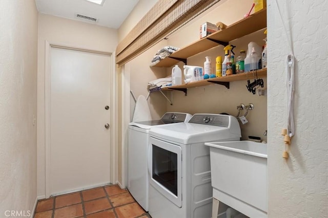 laundry room featuring light tile patterned floors, laundry area, a sink, visible vents, and independent washer and dryer