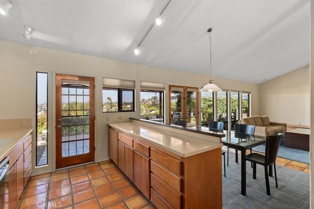 kitchen with brown cabinets, light countertops, vaulted ceiling, a textured ceiling, and a peninsula