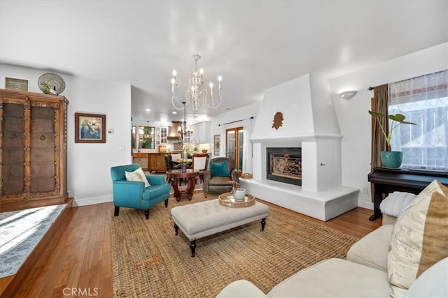 living room featuring baseboards, a fireplace, wood finished floors, and a notable chandelier