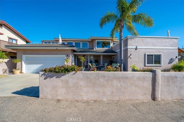 view of front of home featuring concrete driveway, a fenced front yard, an attached garage, and stucco siding