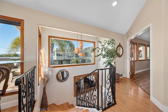 stairway featuring lofted ceiling, baseboards, and wood finished floors