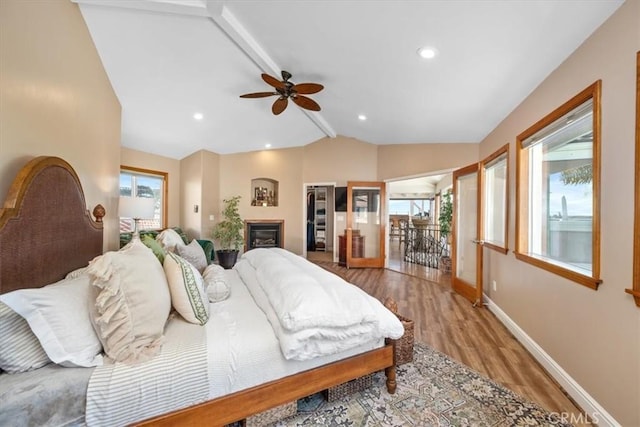 bedroom with lofted ceiling with beams, multiple windows, baseboards, and wood finished floors