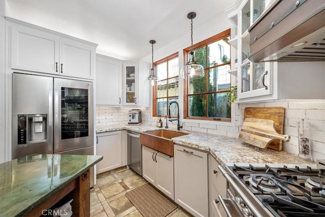 kitchen with pendant lighting, stainless steel appliances, white cabinetry, a sink, and light stone countertops