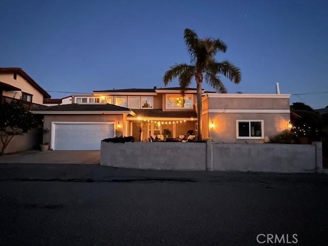 view of front of property with stucco siding, driveway, an attached garage, and solar panels