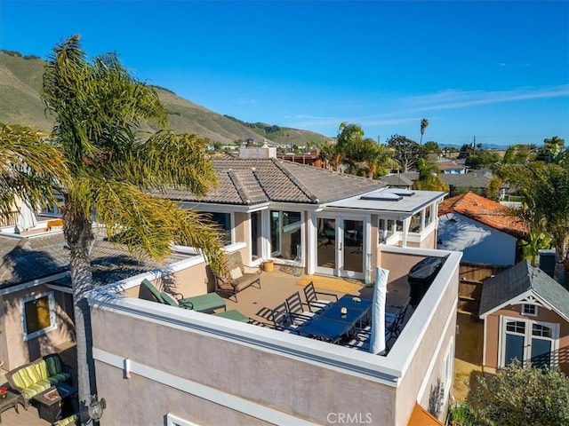 exterior space with french doors, a tile roof, stucco siding, a mountain view, and a balcony