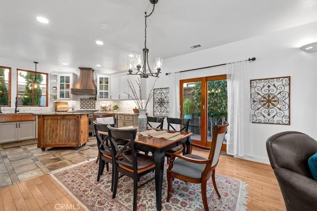 dining space featuring light wood finished floors, an inviting chandelier, visible vents, and recessed lighting