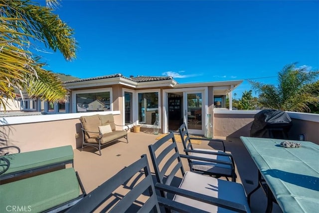 rear view of property with a tile roof, a balcony, and stucco siding