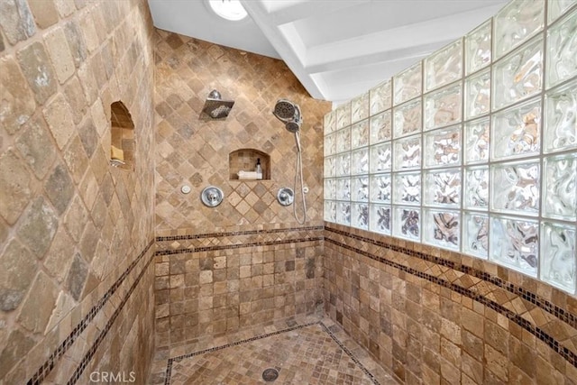 bathroom with beam ceiling and a tile shower