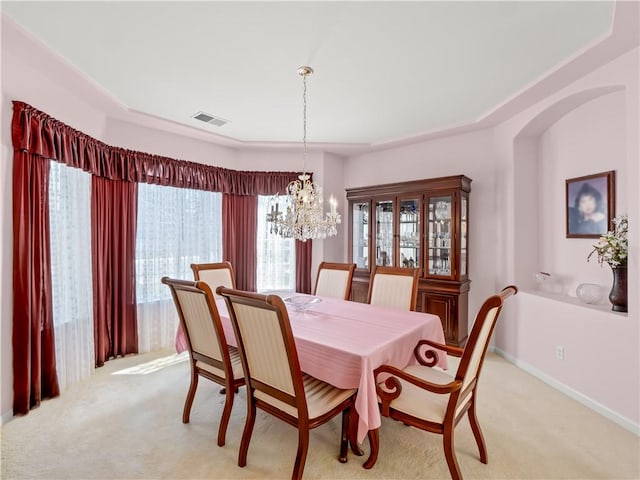 dining area with arched walkways, light colored carpet, visible vents, a chandelier, and baseboards