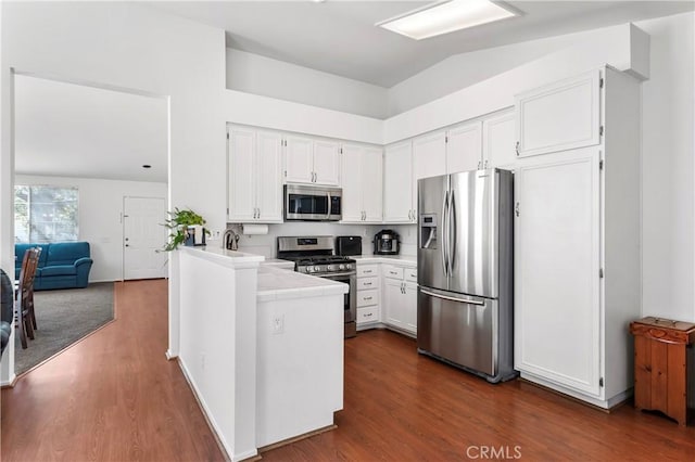 19390 Okeechobee Ln, Lake Elsinore, CA 92530 - kitchen with stainless steel appliances, white cabinetry, dark wood-style floors, a peninsula, and high vaulted ceiling
