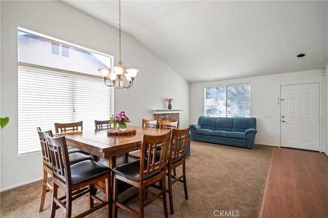 carpeted dining space featuring vaulted ceiling, a brick fireplace, a chandelier, and baseboards