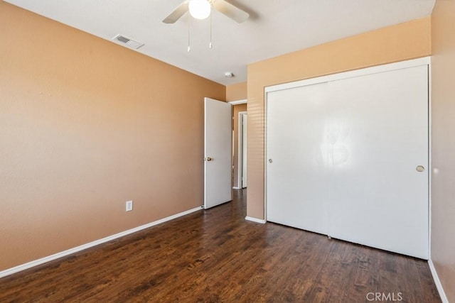 unfurnished bedroom featuring a closet, dark wood-style flooring, visible vents, and baseboards