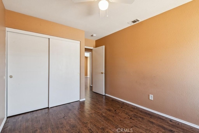 unfurnished bedroom featuring baseboards, visible vents, ceiling fan, wood finished floors, and a closet