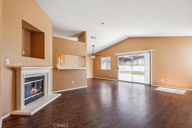 unfurnished living room with visible vents, dark wood finished floors, vaulted ceiling, baseboards, and a glass covered fireplace