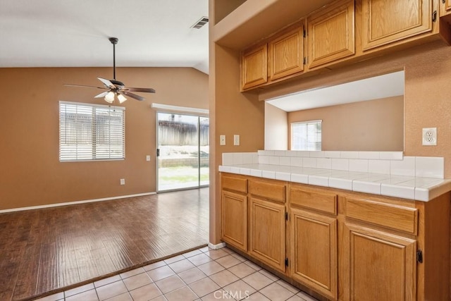 kitchen featuring lofted ceiling, visible vents, a ceiling fan, light wood-type flooring, and brown cabinetry