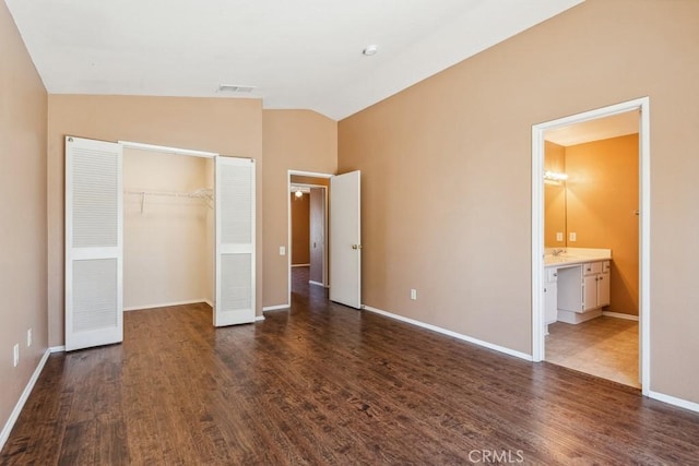 unfurnished bedroom with vaulted ceiling, dark wood-style flooring, a closet, and visible vents