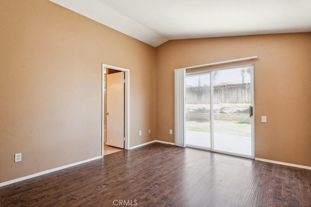 spare room with dark wood-type flooring, vaulted ceiling, and baseboards