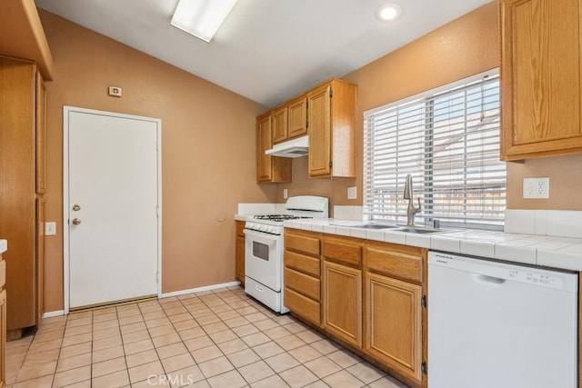 kitchen with light tile patterned floors, under cabinet range hood, white appliances, a sink, and vaulted ceiling