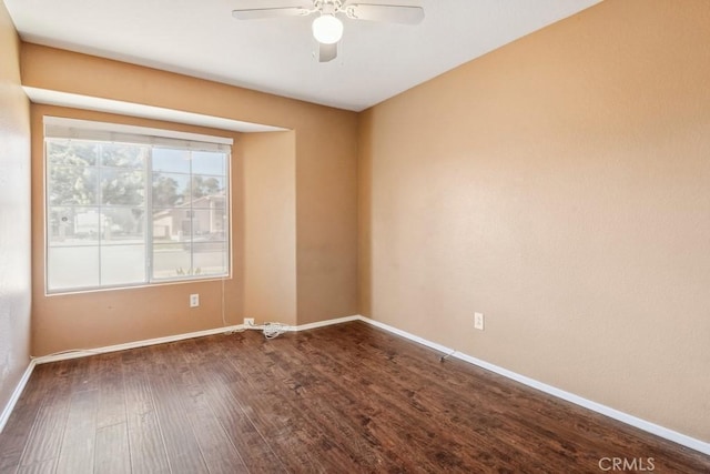 spare room featuring a ceiling fan, dark wood-style flooring, and baseboards