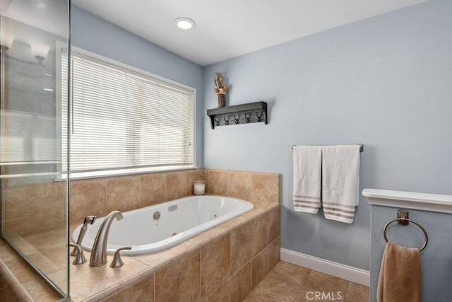 full bath featuring a jetted tub, baseboards, a tile shower, and tile patterned floors