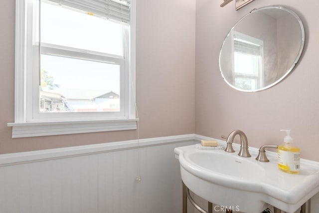 bathroom featuring a sink, a wealth of natural light, and wainscoting