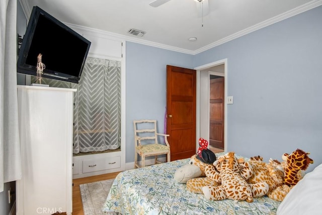 bedroom with ornamental molding, visible vents, ceiling fan, and wood finished floors