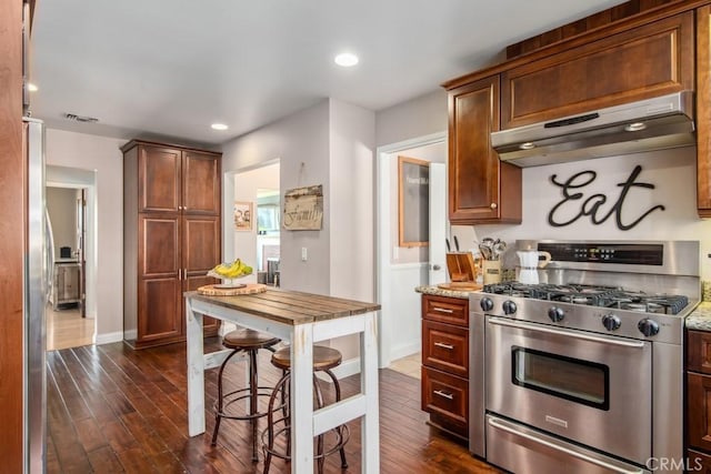 kitchen with visible vents, appliances with stainless steel finishes, dark wood-type flooring, light stone countertops, and under cabinet range hood