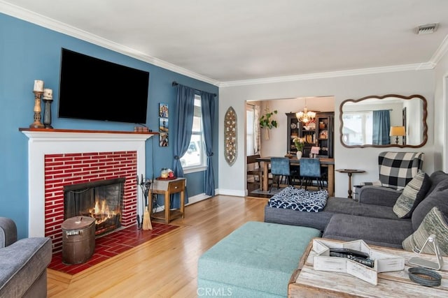 living area featuring a brick fireplace, visible vents, crown molding, and wood finished floors