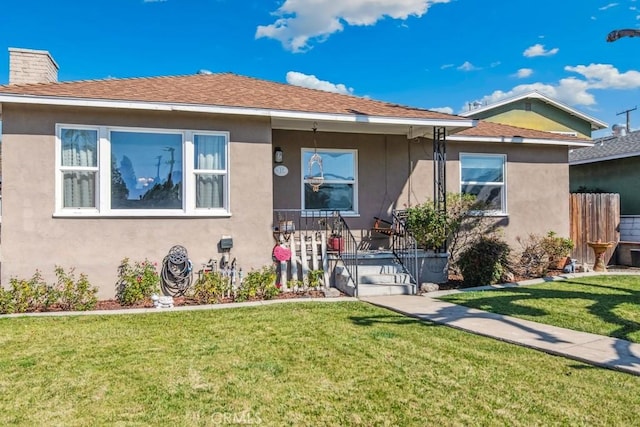 bungalow-style home with stucco siding, roof with shingles, a chimney, and a front yard