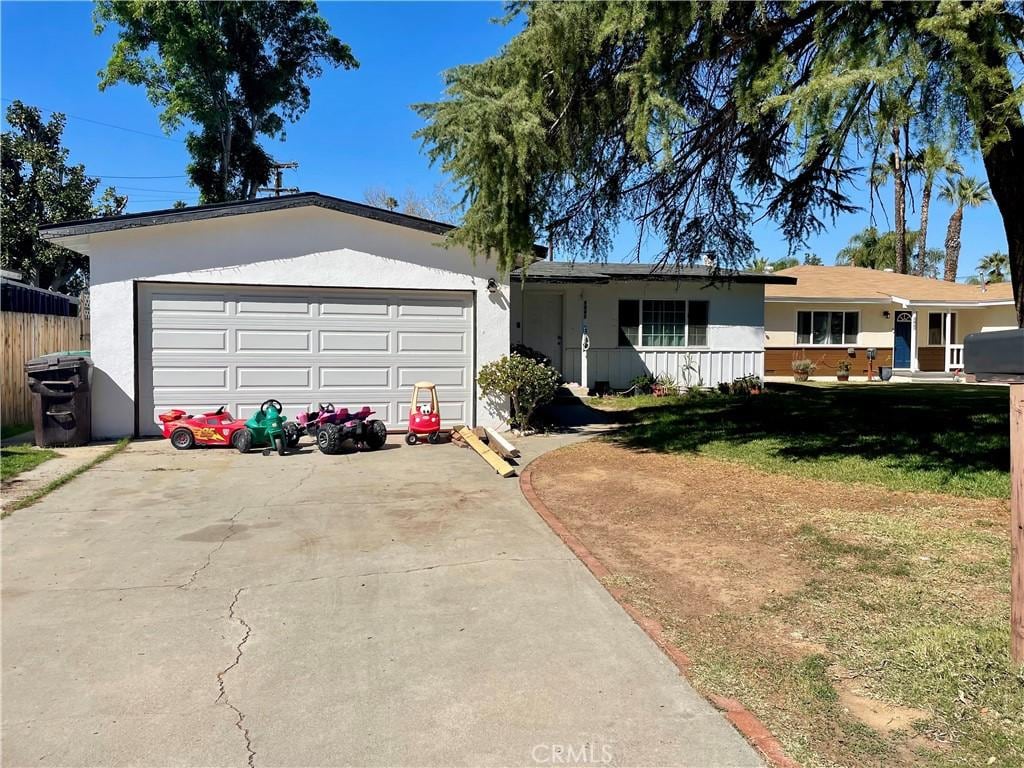 ranch-style house featuring an attached garage, driveway, a front lawn, and stucco siding