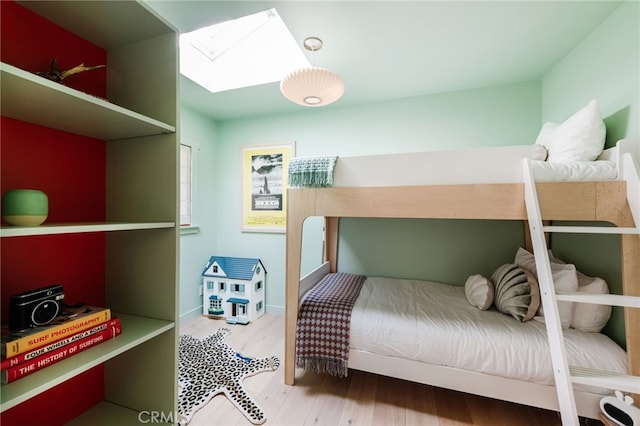 bedroom featuring a skylight and wood finished floors