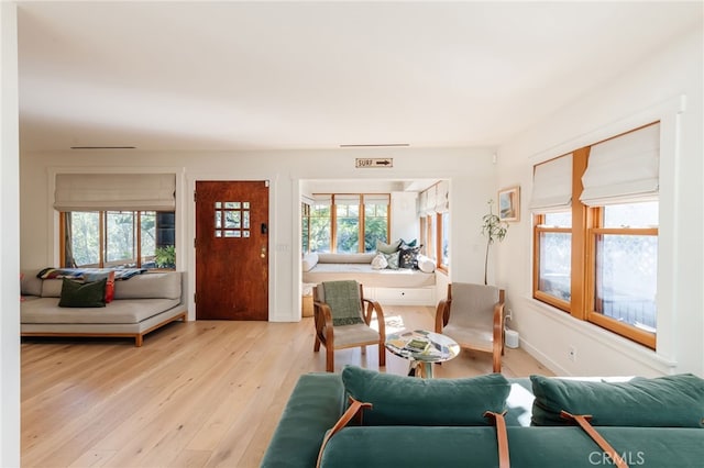 living room with plenty of natural light, light wood-type flooring, and baseboards