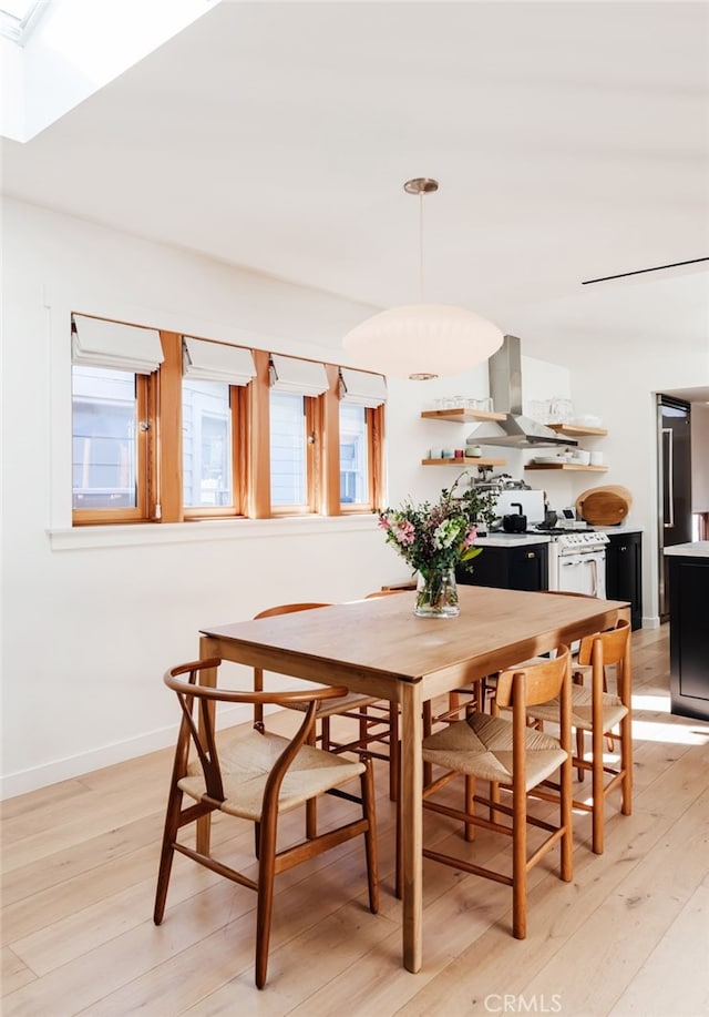 dining room with baseboards, light wood-style flooring, and a healthy amount of sunlight