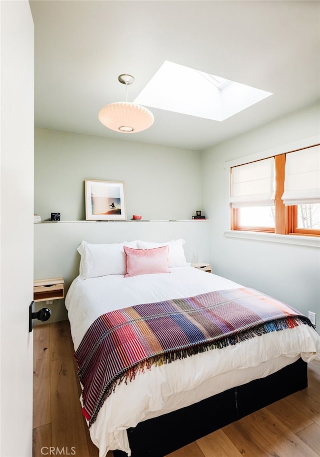 bedroom featuring a skylight and wood finished floors