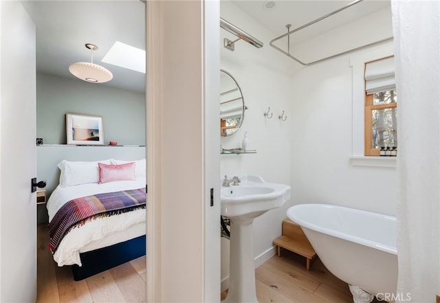 ensuite bathroom with a soaking tub, connected bathroom, and wood finished floors