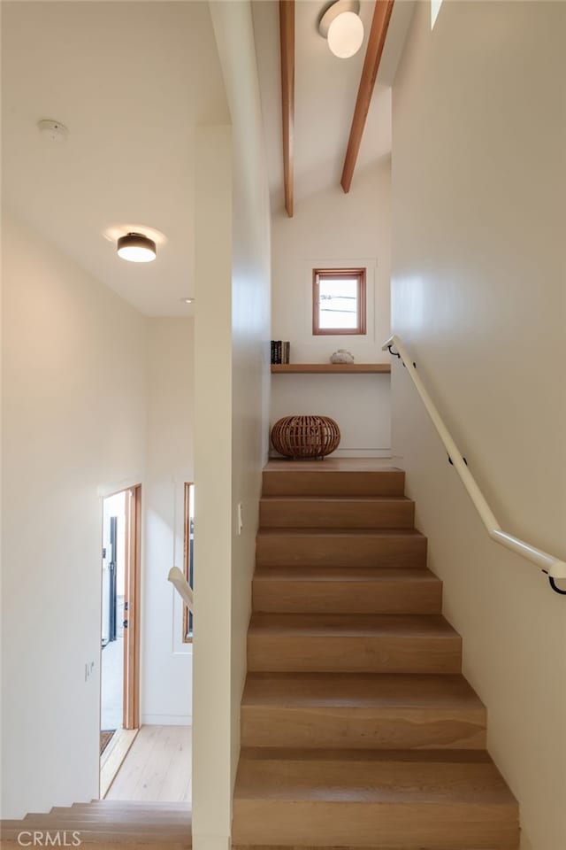 stairway featuring high vaulted ceiling, wood finished floors, and beam ceiling