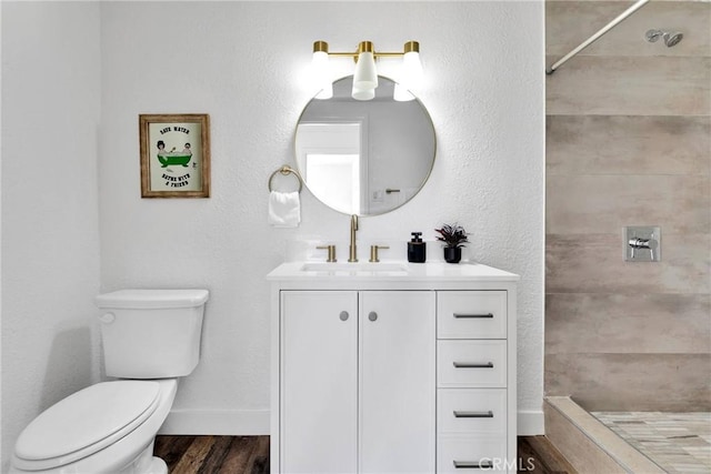 full bath featuring tiled shower, wood finished floors, toilet, and baseboards