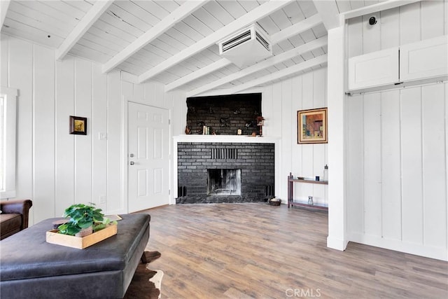 living area featuring vaulted ceiling with beams, a fireplace, visible vents, wood finished floors, and baseboards