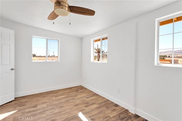 unfurnished room with ceiling fan, plenty of natural light, baseboards, and wood finished floors