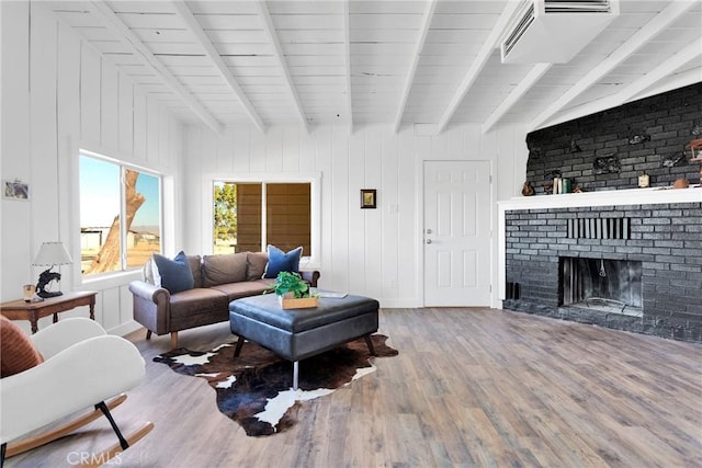 living area with a fireplace, wood finished floors, and beam ceiling