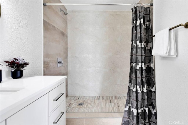 full bathroom featuring a tile shower and vanity