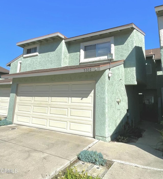 view of front of home featuring an attached garage, concrete driveway, and stucco siding