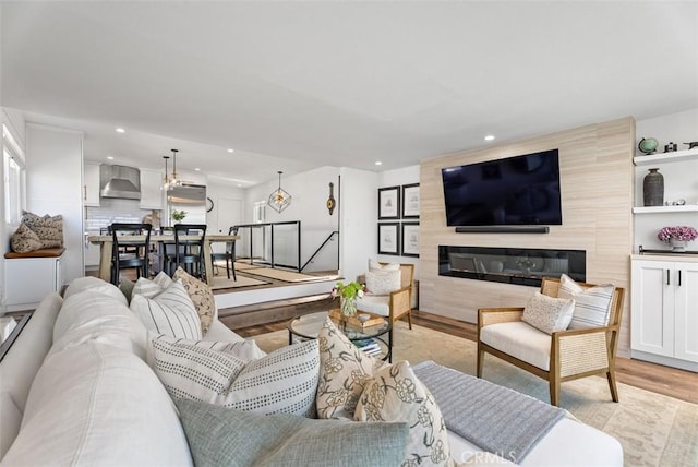 living room with light wood-style floors, recessed lighting, and a large fireplace