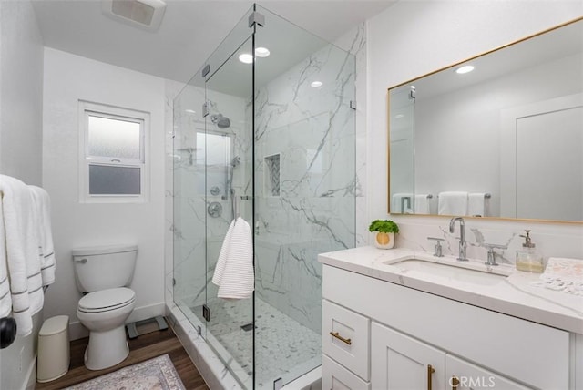 full bathroom featuring a marble finish shower, toilet, wood finished floors, vanity, and recessed lighting