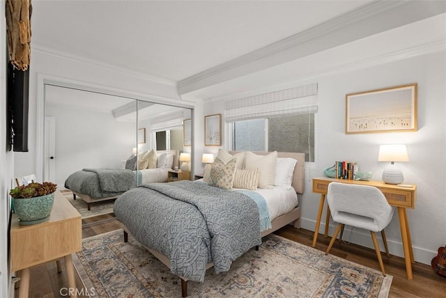 bedroom featuring baseboards, a closet, ornamental molding, and wood finished floors