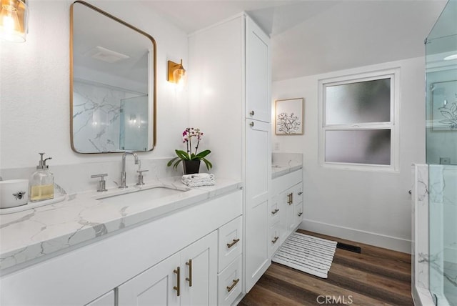 full bath with baseboards, vanity, a marble finish shower, and wood finished floors