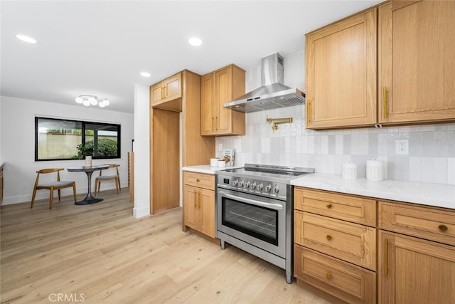 kitchen with decorative backsplash, light countertops, wall chimney range hood, and stainless steel electric range